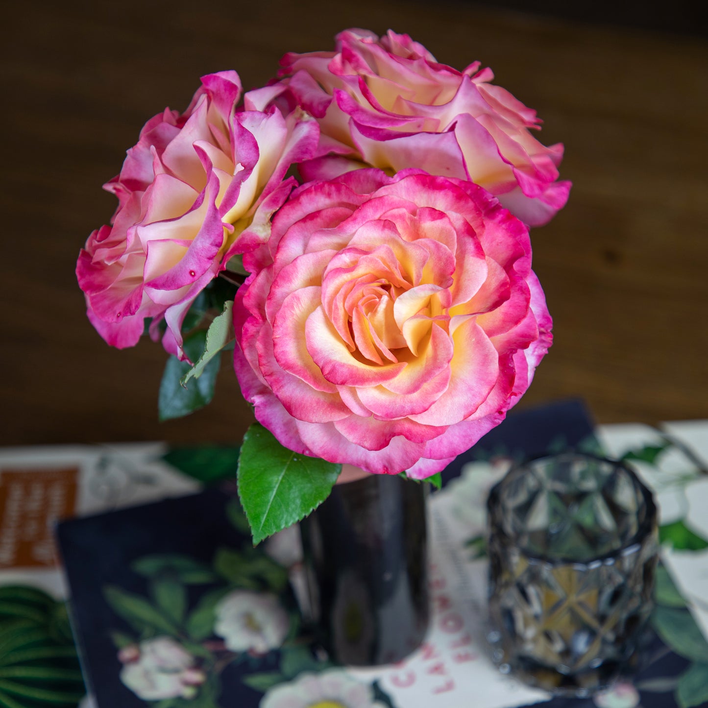 Bouquet of pink and yellow roses in a black vase on a decorative table.